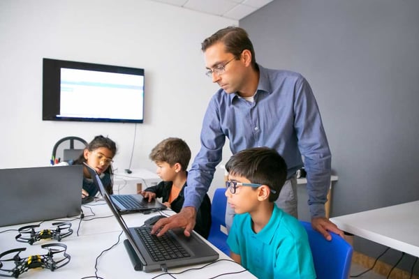 Teacher helping students work on computer projects in flipped classroom
